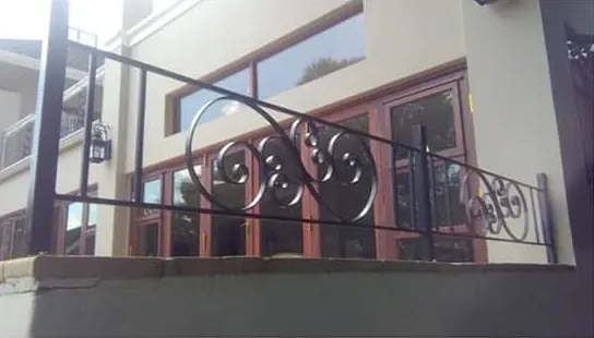 Black steel balcony balustrade with decorative scroll panels