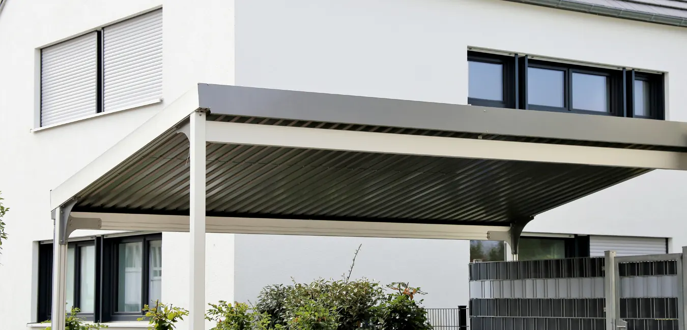 Modern steel carport with a flat roof attached to a white house