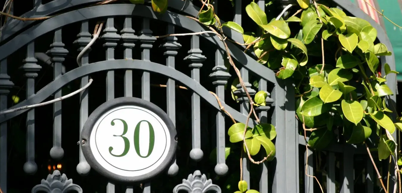 Grey decorative steel gate with a house number plate