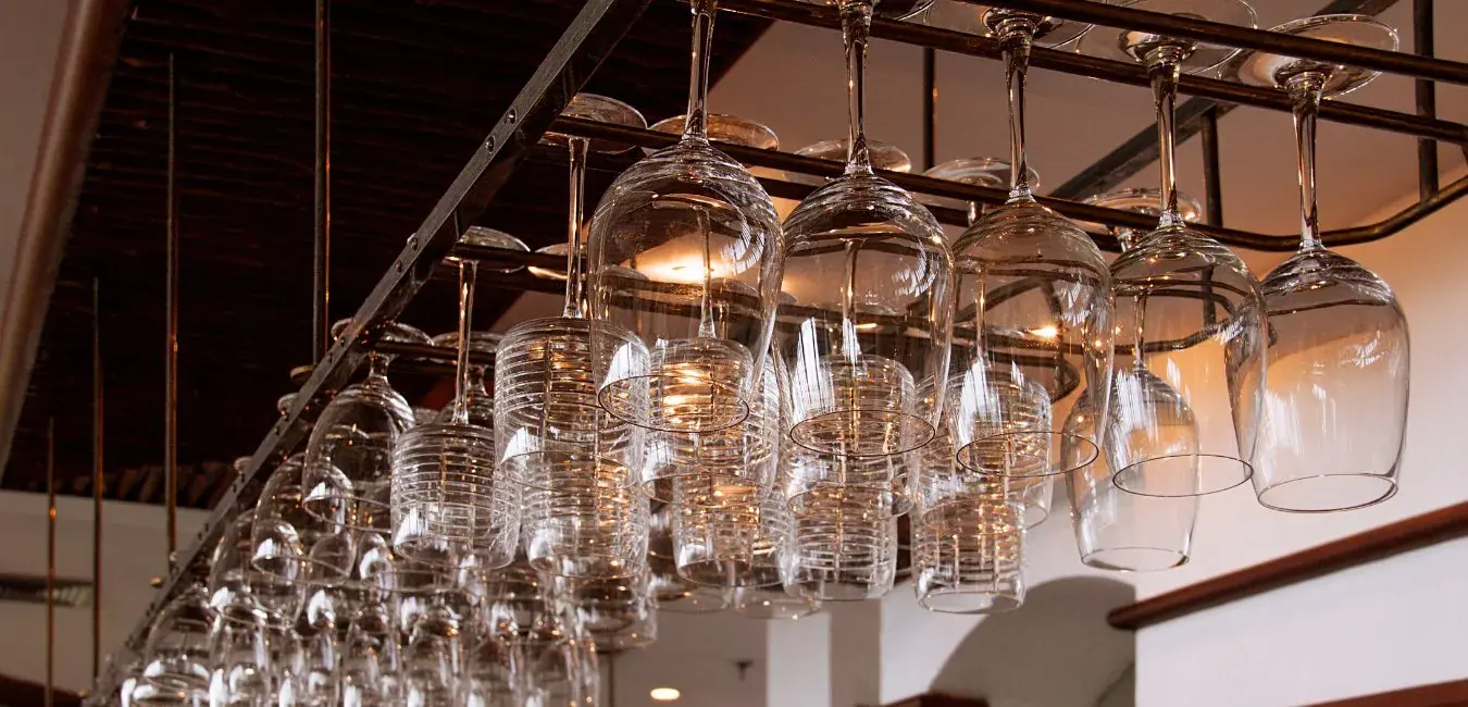 Custom steel wine-glass rack hanging above a bar